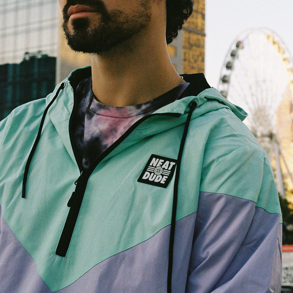 closeup detail shot of neatdude windbreaker, showing a stamped rubber patch of the neat dude globe logo